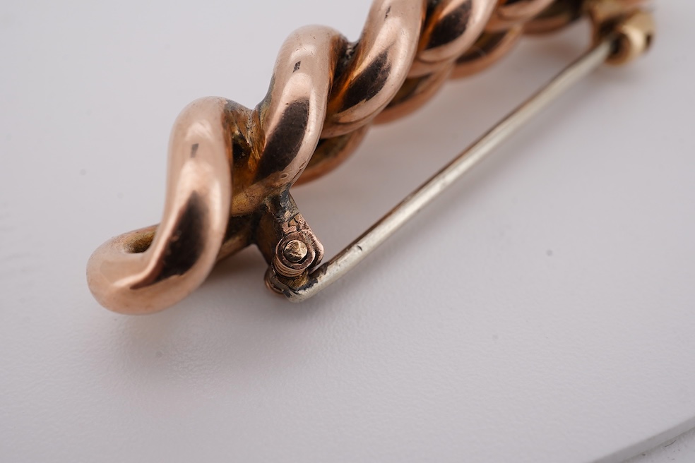 An early 20th century yellow metal and graduated five stone coral bead brooch, with seed pearl spacers, 45mm, together with a yellow metal curb link brooch and a yellow metal (stamped 9c) safety pin. Condition - fair